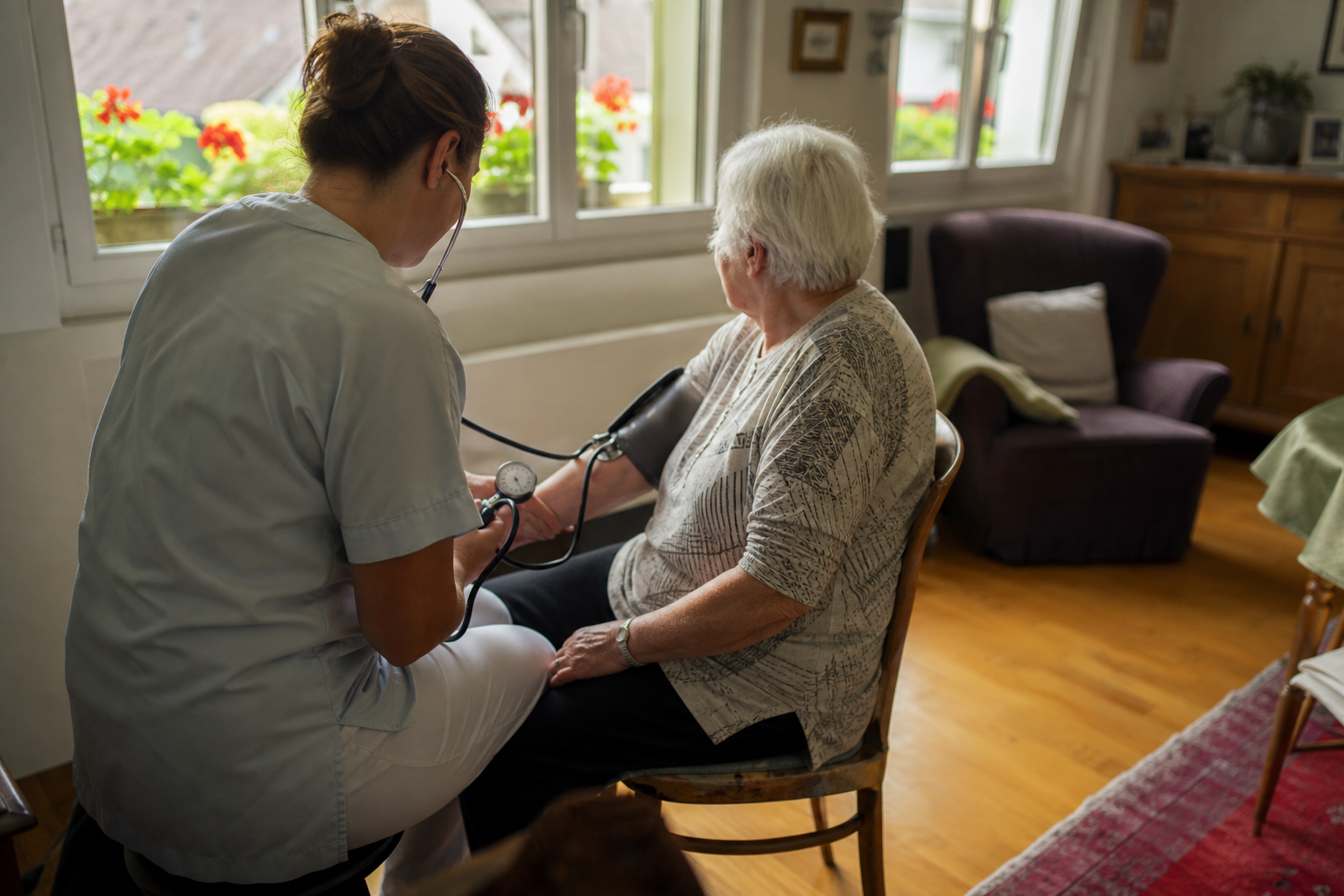 A home care nurse checking the blood pressure of an elderly patient in a Swiss living room